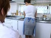キッチンで食事の準備をするエプロン姿の義母を後ろから